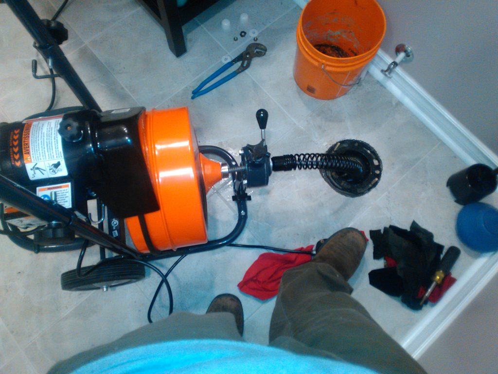 A drain machine with its cable running into a floor drain