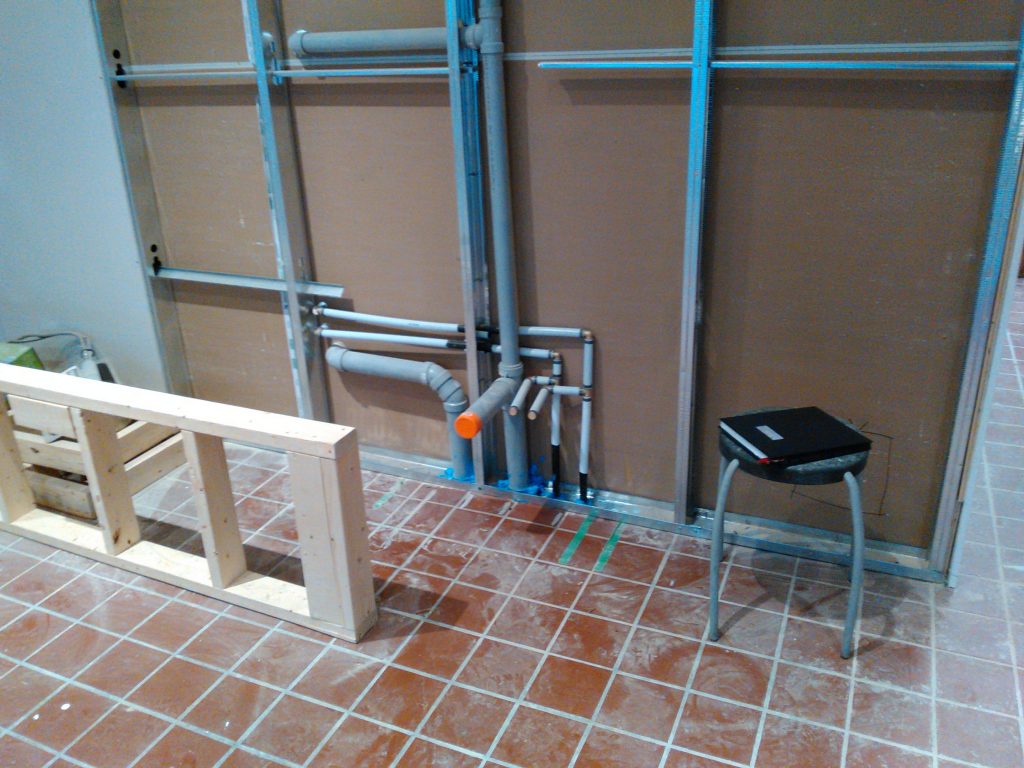 New drain and supply rough-in piping on a framed wall, before the drywall goes up